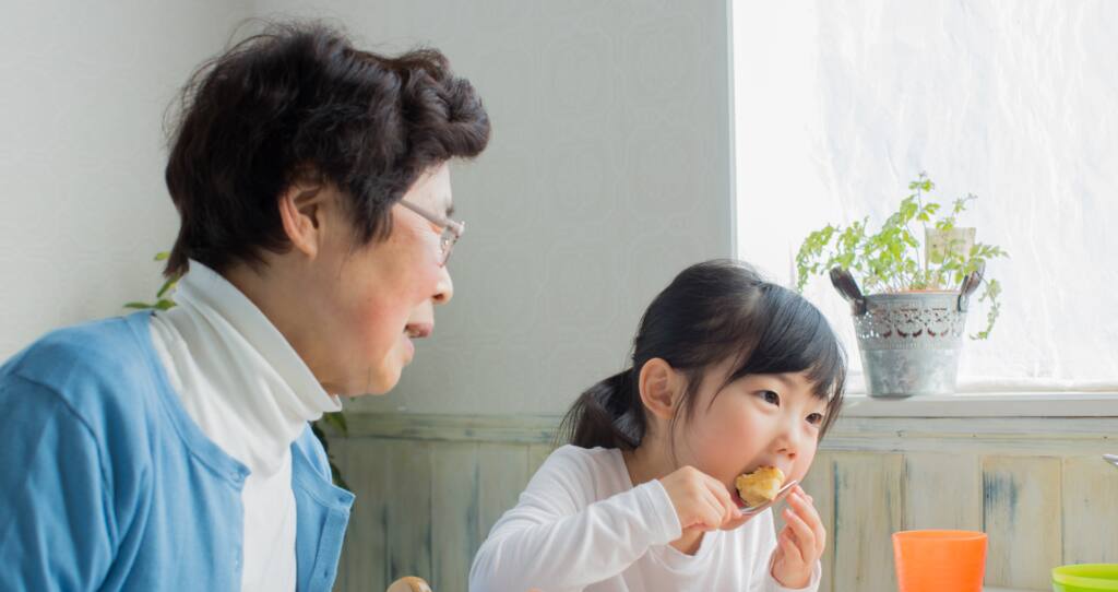 おばあちゃんと孫が食事をしているイメージ写真